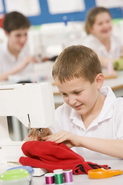 Schoolboy using a sewing machine in sewing class — Stock Photo, Image