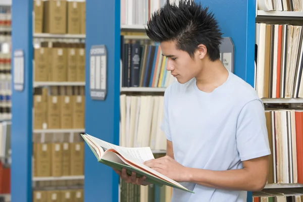 Estudante universitário leitura na biblioteca — Fotografia de Stock