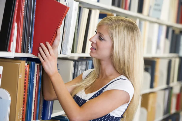 Estudiante universitario seleccionando libro de biblioteca — Foto de Stock
