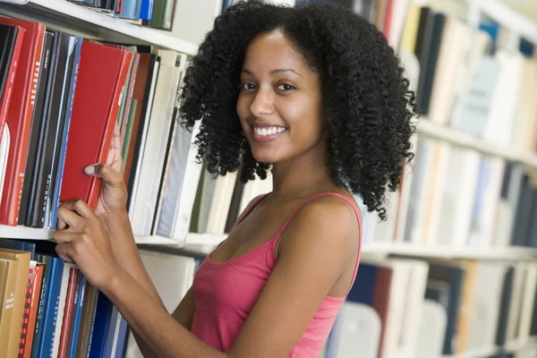 Студент університету вибирає книгу з бібліотеки — стокове фото