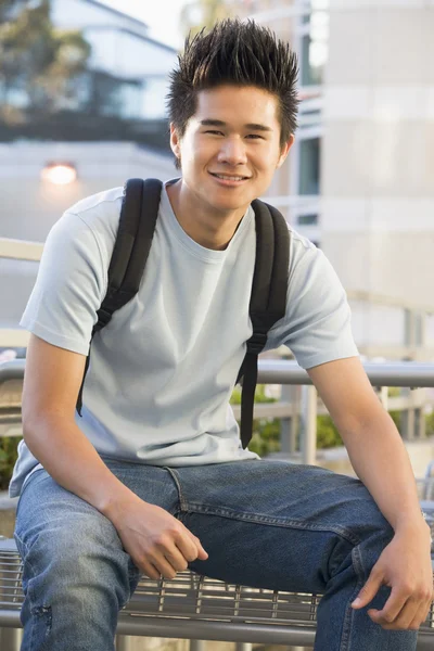 リュックサックを着て外に座っている男性大学生 — ストック写真