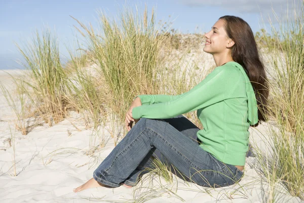 Young woman sitting in sand dunes — Stock Photo, Image