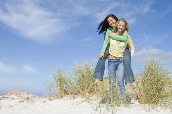 两名年轻妇女在沙丘背驮式开心 — 图库照片