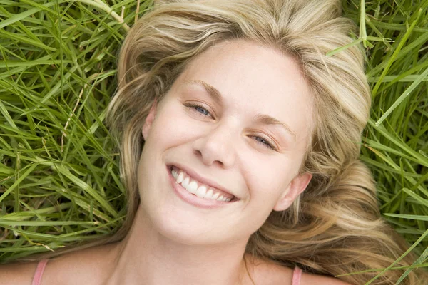年轻女人躺在草到相机微笑的顶视图 — 图库照片