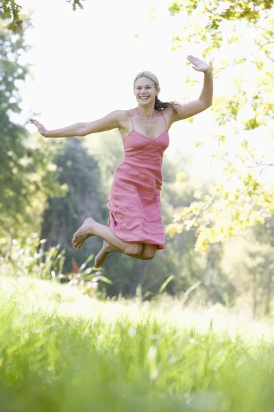 年轻女子在夏天草地上跳跃 — 图库照片