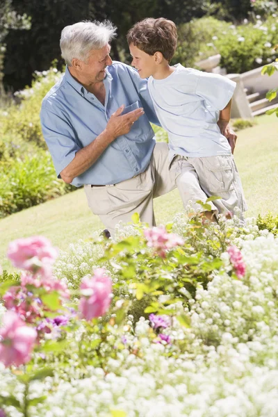 Avô e neto ao ar livre no jardim falando e sorrindo — Fotografia de Stock