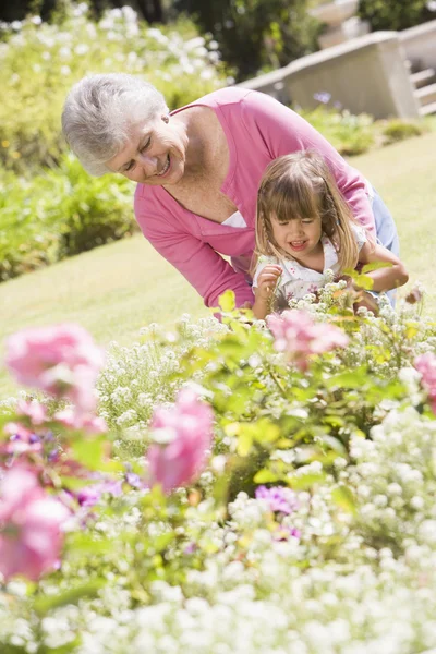 Бабушка и внучка на улице в саду улыбаются — стоковое фото