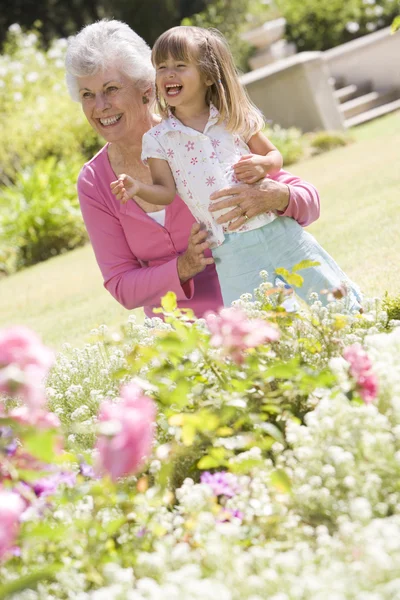 Grandmother and granddaughter outdoors in garden smiling — Stock Photo, Image