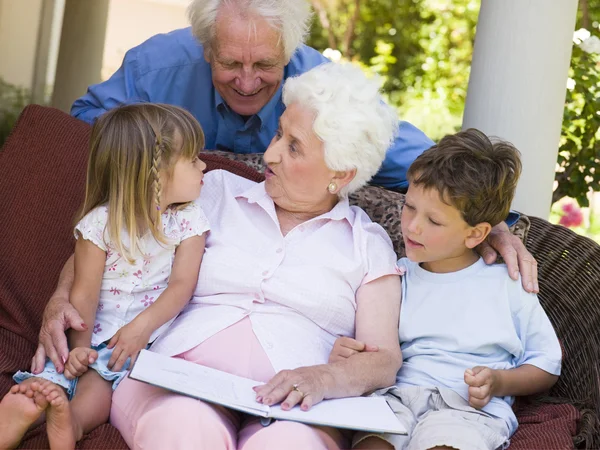 Бабушка с дедушкой читают внукам — стоковое фото