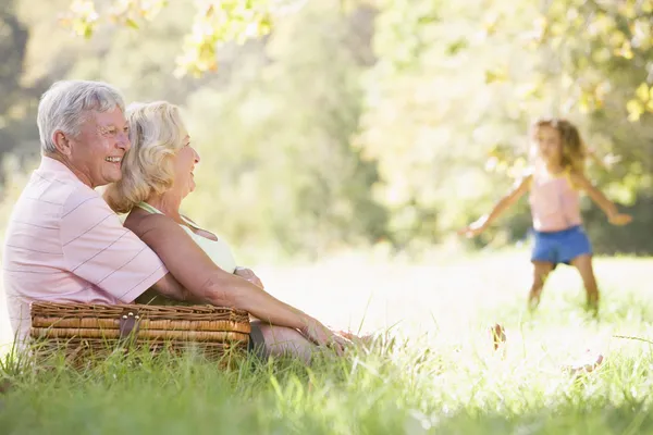 Großeltern bei einem Picknick mit jungen Mädchen im Hintergrund tanzen — Stockfoto