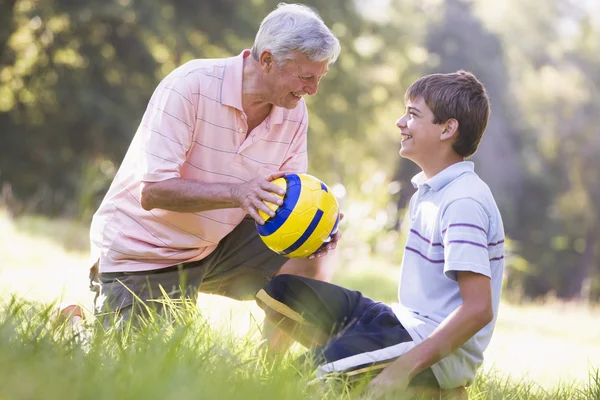 Дідусь і онук в парку з м'ячем посміхаючись — стокове фото