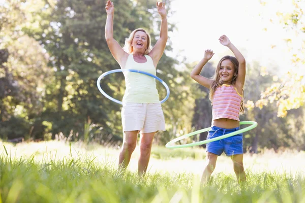 Grandmother and granddaughter at a park hula hooping and smiling — Stock Photo, Image