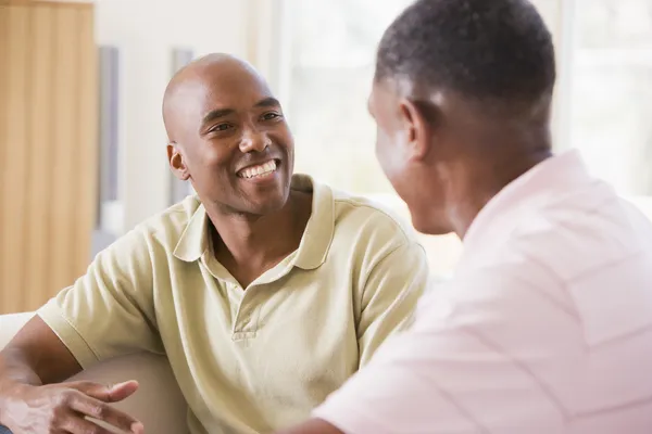 Two men in living room talking and smiling — Stock Photo, Image