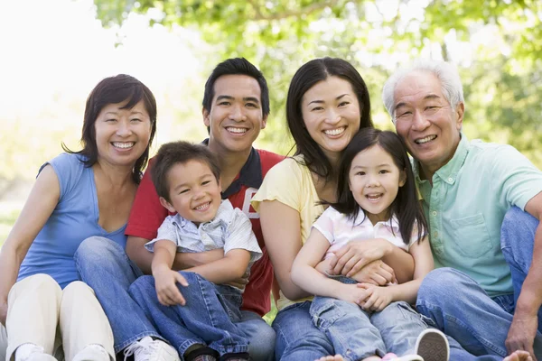 Extended family sitting outdoors smiling — Stock Photo, Image