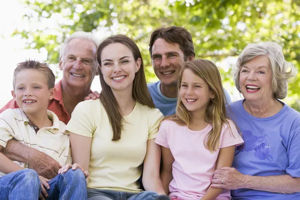 Розширена сім'я сидить на відкритому повітрі посміхаючись — стокове фото