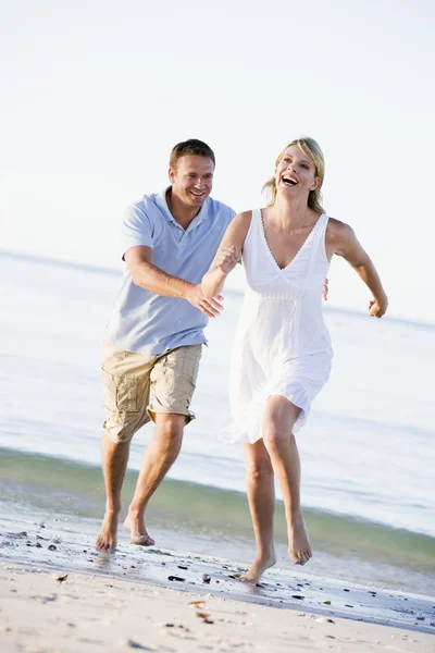 Пара на пляже играет и улыбается — стоковое фото