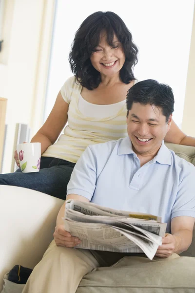 Couple relaxing with a newspaper and smiling — Stock Photo, Image