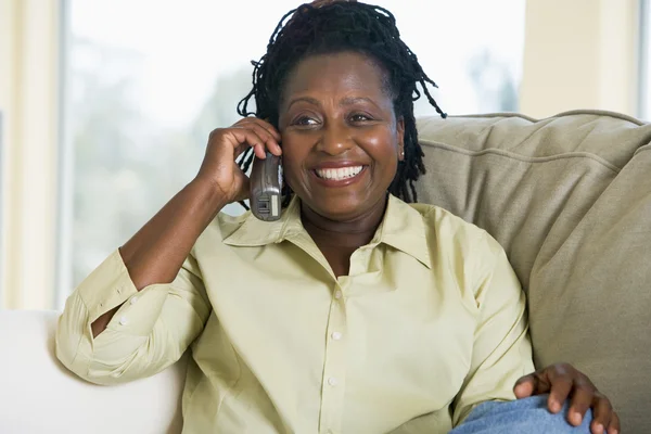Femme assise dans le salon en utilisant le téléphone et souriant — Photo