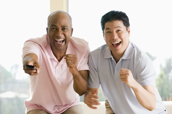 Dos Hombres Sala Estar Con Control Remoto Animando Sonriendo — Foto de Stock