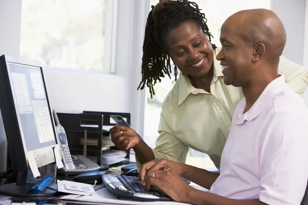 Пара в домашнем офисе с кредитной картой с помощью компьютера и улыбкой — стоковое фото
