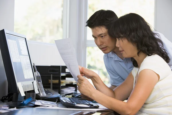 Couple in home office with computer and paperwork pointing — Stock Photo, Image