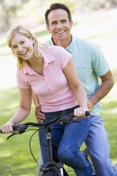 Para na jeden rower na zewnątrz uśmiechający się — Zdjęcie stockowe