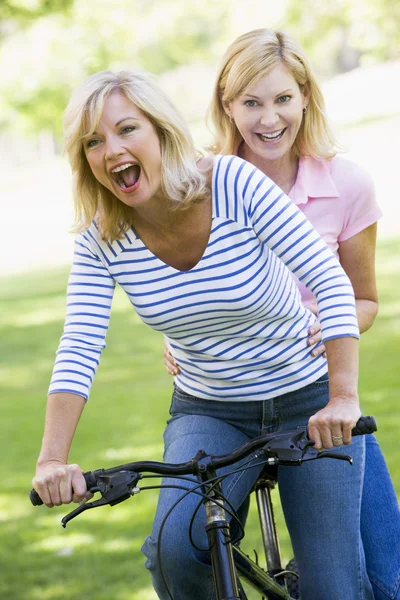 Два друга на одном велосипеде снаружи улыбаются — стоковое фото