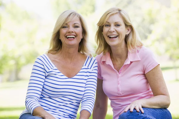 Dwie Kobiety Siedzące Zewnątrz Uśmiechnięte — Zdjęcie stockowe
