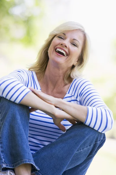 Женщина сидит на улице и смеется. — стоковое фото