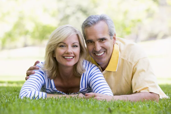 Couple relaxing outdoors in park smiling — Stock Photo, Image