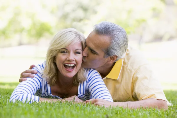 公園キスと笑みを浮かべて屋外でリラックスしたカップル — ストック写真