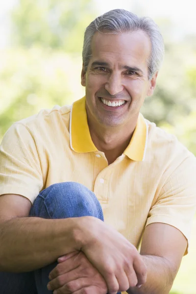 Homem sentado ao ar livre sorrindo — Fotografia de Stock