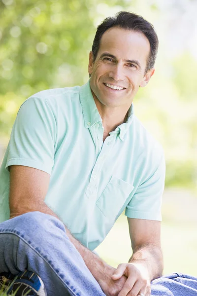 Man sitting outdoors smiling — Stock Photo, Image