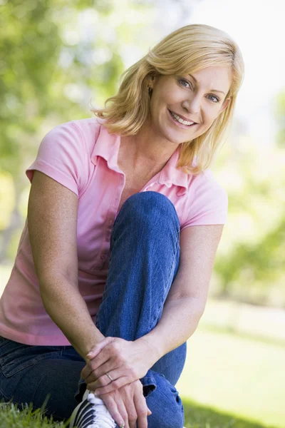Kvinna som sitter utomhus leende — Stockfoto
