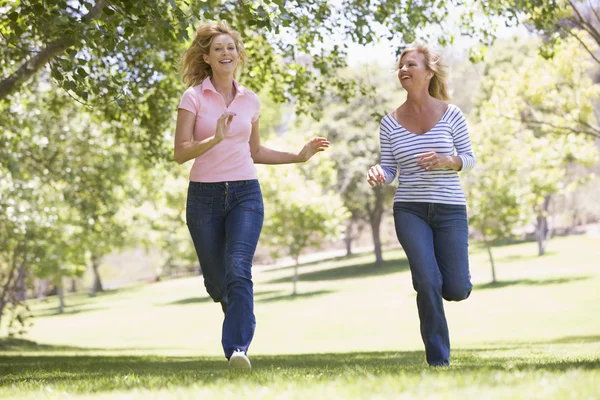 Две женщины бегут в парке и улыбаются — стоковое фото