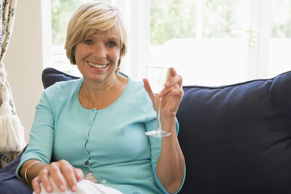 Mujer sentada en la sala de estar con bebida sonriendo —  Fotos de Stock