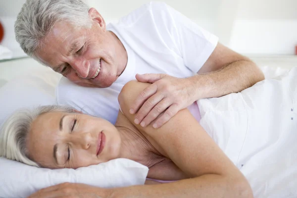 Mann weckt schlafende Frau im Bett — Stockfoto