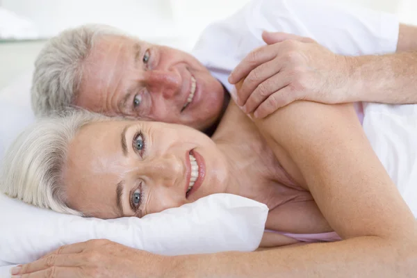 Paar lächelnd im Bett liegend — Stockfoto
