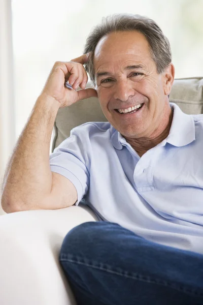 Mann sitzt lächelnd im Wohnzimmer — Stockfoto