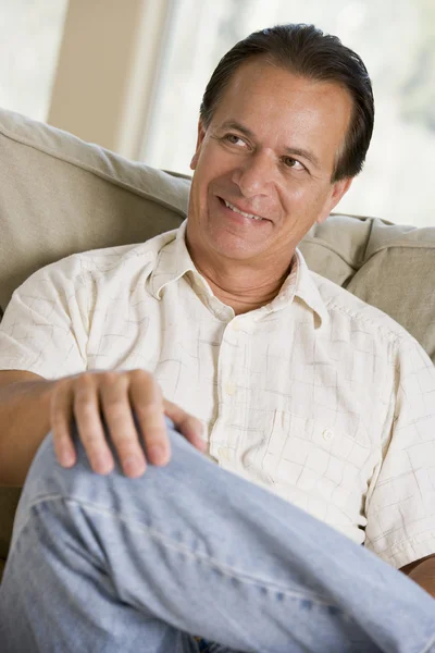 Muž sedí v obýváku s úsměvem — Stock fotografie