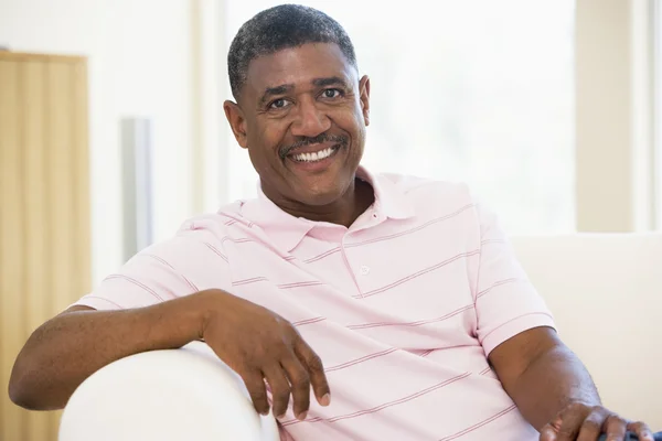 Muž sedí v obýváku s úsměvem — Stock fotografie