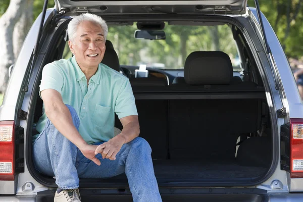 Hombre sentado en la parte trasera de la camioneta sonriendo —  Fotos de Stock