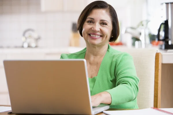 在厨房里用笔记本电脑微笑的女人 — 图库照片