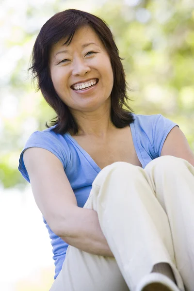 Kvinna som sitter utomhus leende — Stockfoto