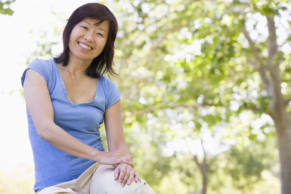 Woman sitting outdoors smiling — Stock Photo, Image