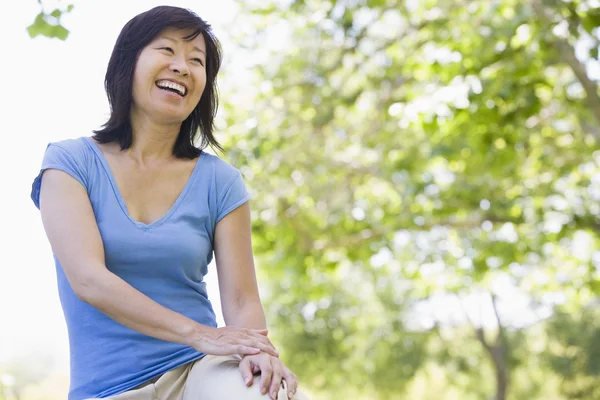 Mujer sentada al aire libre sonriendo — Foto de Stock