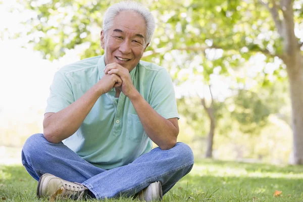 Hombre sentado al aire libre sonriendo — Foto de Stock
