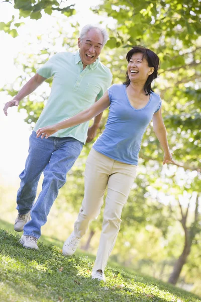 Пара бегущих на свежем воздухе в парке у озера улыбающихся — стоковое фото