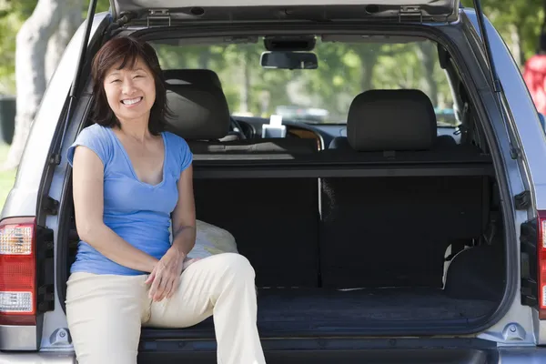 Mujer sentada detrás de la furgoneta sonriendo — Foto de Stock