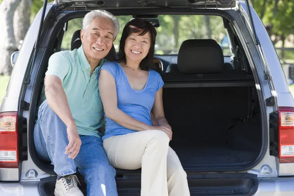 Пара сидить позаду фургона посміхаючись — стокове фото